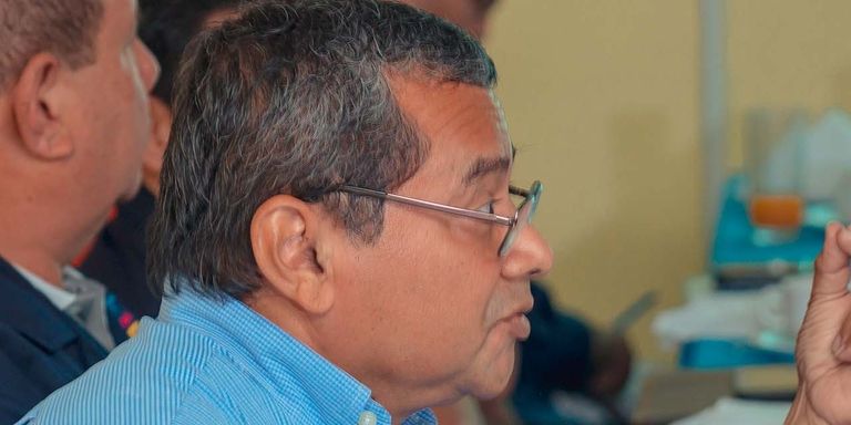 A man wearing glasses speaking in a meeting