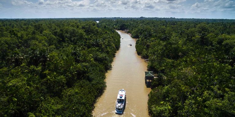 Embarcación navegando por un río en medio de zona selvática. Desarrollo sostenible - Banco Interamericano de Desarrollo - BID 