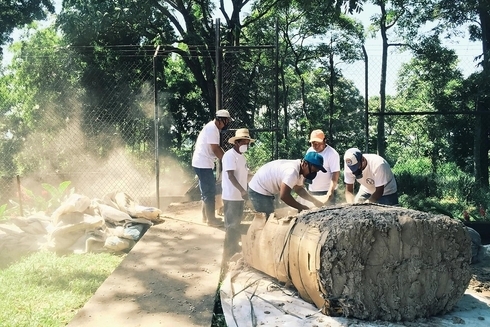 A group of people in a workshop filled with textile machinery and fabric materials, working together on a sustainable denim project - Sustainable Development - Inter-American Development Bank - IDB 